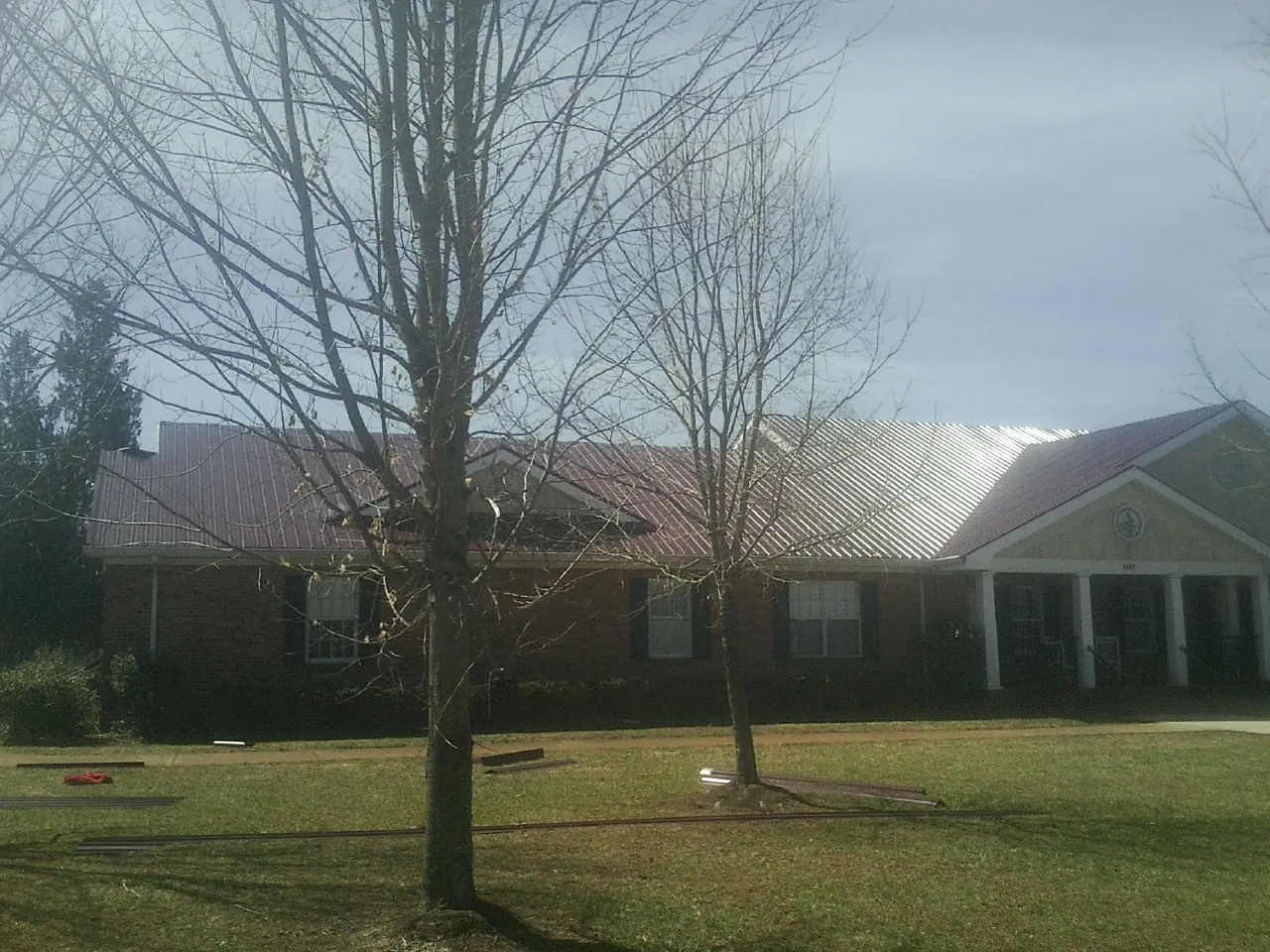 Red metal roof on a brick building seen from the front lawn in Willow Springs