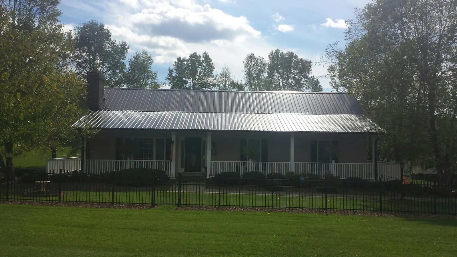 Gray metal roof on a brick ranch with a full width front porch — Gutter Guard Installation work by our crew in Willow Springs